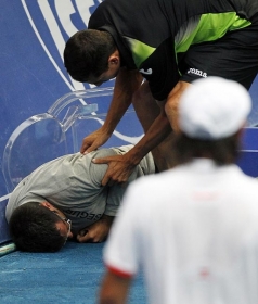 O tenista Guillermo Garcia-Lopez ajuda o juiz que desmaiou durante jogo contra o cipriota Baghdatis (de costas)