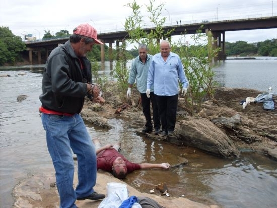 Corpo sendo retirado do rio por peritos da Politec
