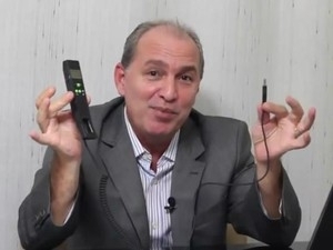 Diretor Carlos Costa com telefone VoIP, tecnologia que empresa alega comercializar, em vdeo na internet (Foto: Reprodu