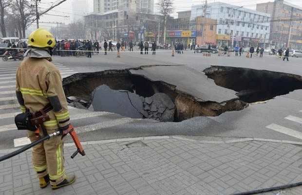 Policial guarda o buraco misterioso nesta quarta-feira (26) na cidade chinesa de Taiyuan (Foto: Reuters)