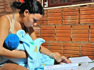 Pmela com o filho Everton no colo e os livros espalhados pela cama (Foto: Tatiane Queiroz/ G1MS)