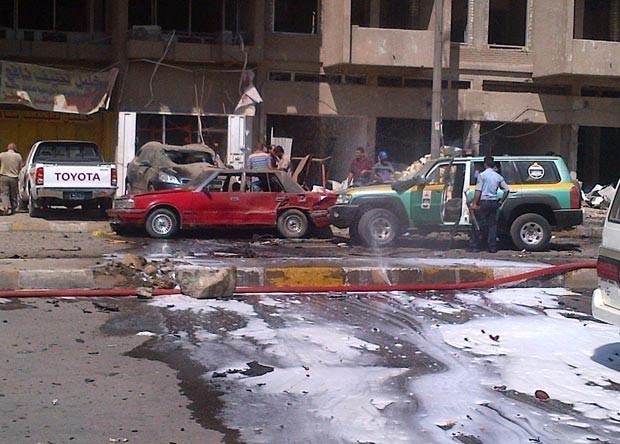 Policiais observam carro-bomba que explodiu neste domingo (30) em Karrada, em Bagd (Foto: AFP)