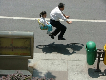 Homem carrega menina em bibicleta invisvel em rua da China (Foto: Zhao Huasen).