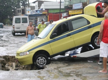 Txi cai em buraco durante chuva em Campo Grande 