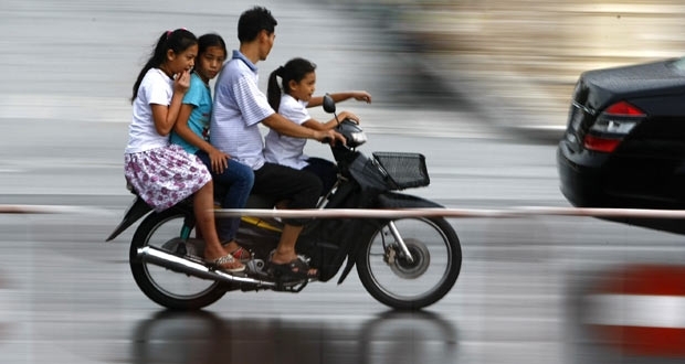 Motociclista anda com motoneta superlotada Phnom Penh.