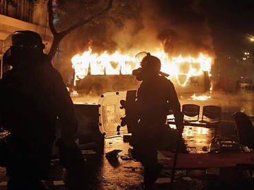 Policial caminha em frente a nibus queimado por black blocs durante protesto no Rio. A manifestao  para exigir mudan