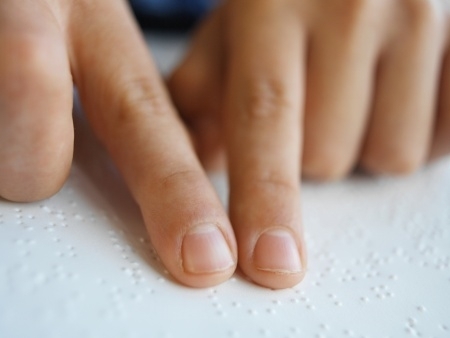 Homem cego utiliza sistema de linguagem braile para ler livro